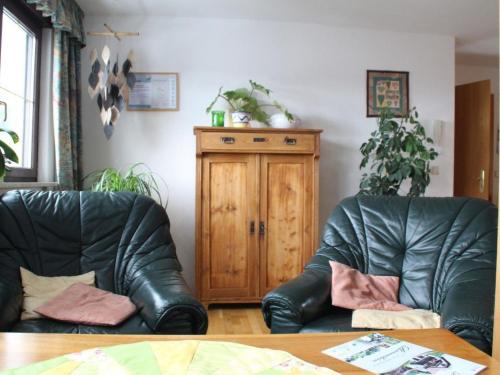 two black leather chairs in a living room with a wooden cabinet at Apartment FeWo Panorama by Interhome in Rauenstein