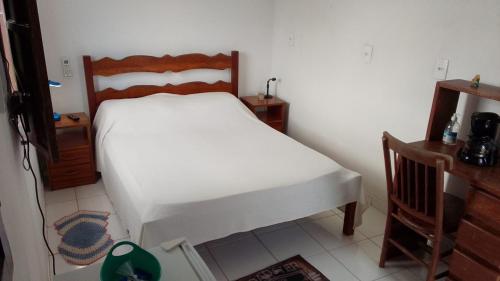 a bedroom with a white bed with a wooden headboard at Casa Rosa da Ilha - Suíte com Ar-condicionado e Jardim Amplo in Vera Cruz de Itaparica