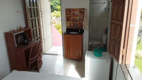 a room with a kitchen with a refrigerator and a door at Casa Rosa da Ilha - Suíte com Ar-condicionado e Jardim Amplo in Vera Cruz de Itaparica