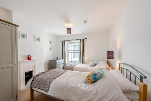 two beds in a white bedroom with a fireplace at 3 Bed in Appledore oc-phoe in Appledore