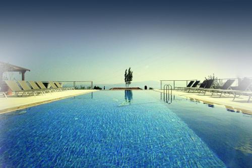 a large blue swimming pool with chairs and the ocean at Assos Sunaba Kasri Hotel in Behramkale