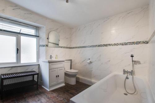 a white bathroom with a tub and a toilet at 3 Bed in Appledore oc-phoe in Appledore