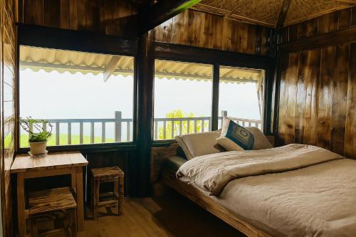a bedroom with a bed and a table and windows at Sapa Local Guide Homestay Trek 2 Days 1 Night or Multi-Day Trekking in Lao Cai