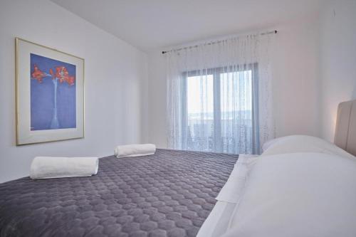 a white bedroom with a large bed and a window at Bella Vista Dalmatien in Čelina