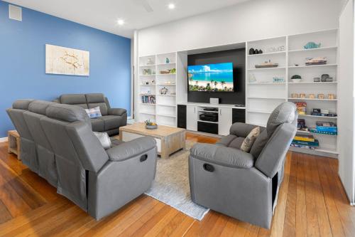 a living room with two chairs and a flat screen tv at Coffs Jetty Beach House in Coffs Harbour