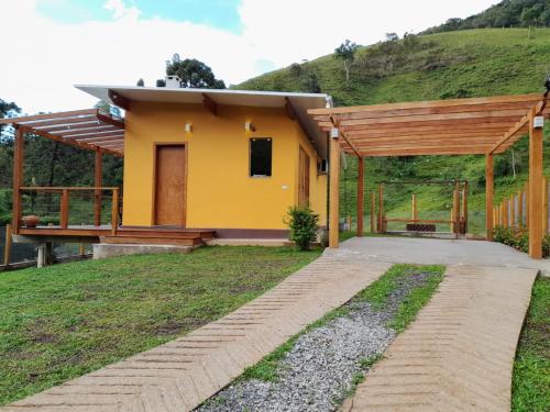 a small yellow house with a hill in the background at Chalé Topázio Gonçalves in Gonçalves