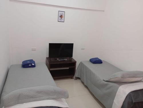 a room with two beds and a tv in it at Dpto Los Pinos in Fernández