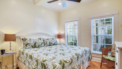 a bedroom with a bed and two windows at Paradise Place by AvantStay Key West Old Town Condo w Shared Pool in Key West