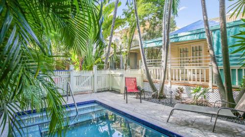 a house with a swimming pool and palm trees at Paradise Place by AvantStay Key West Old Town Condo w Shared Pool in Key West