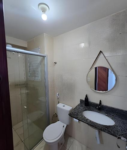 a bathroom with a toilet and a sink and a mirror at Apartamento Cantinho do Mar in Natal