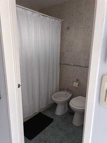 a bathroom with a toilet and a white shower curtain at Clima Termal Suites in Federación
