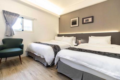 a hotel room with two beds and a chair at T and C 民宿 in Wujie