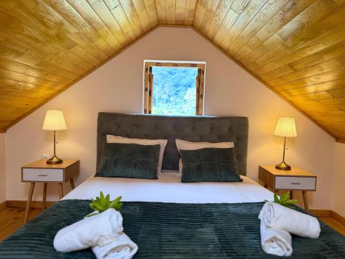 a bedroom with a large bed with two lamps at Casa do Til in Porto Moniz