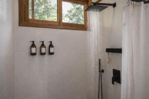 a bathroom with a shower with three bottles on the wall at La Casa Selva in Bocas Town