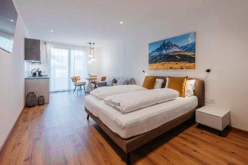 a bedroom with a large bed and a kitchen at ecHo Apartments & SPA in Bressanone