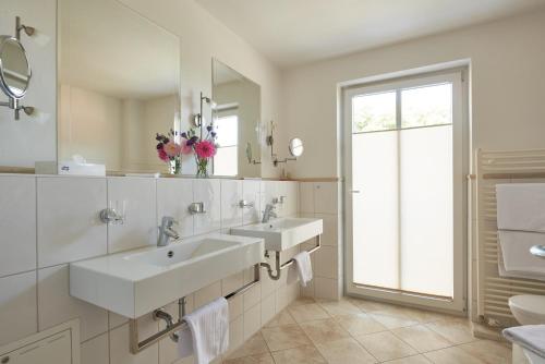 a white bathroom with two sinks and a window at Hotel & Restaurant Alte Schule in Siek