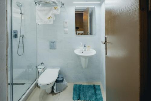 a bathroom with a toilet and a sink and a shower at The Avery Apartments, Dzorwulu in Accra