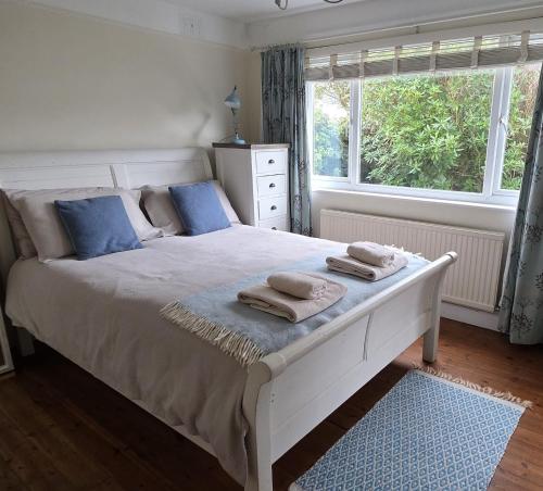 a bedroom with a white bed with towels on it at Cosy room, en-suite with kitchenette in St. Davids