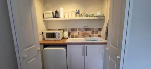a small kitchen with a sink and a microwave at Cosy room, en-suite with kitchenette in St. Davids