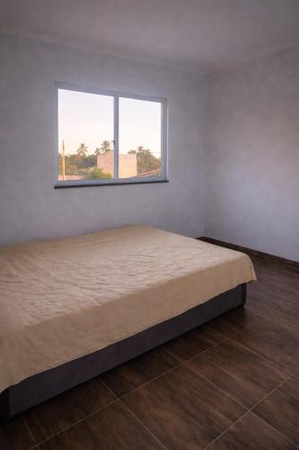 a bedroom with a large bed with a window at Lajedalu in Aquiraz