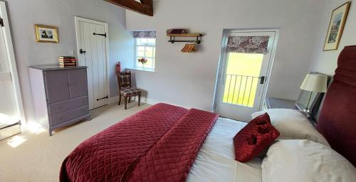 a bedroom with a large bed with a red blanket at Rowsley Cottage Bakewell Peak District in Bakewell
