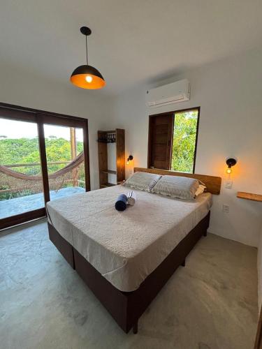 a bedroom with a large bed in a room with windows at CASA NANDOS Flat Essência !!! in Itacaré
