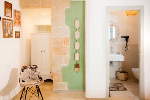 a bathroom with a stone wall and a chair at Profumo Antico - Luxury Guesthouse by STHEY in Monopoli