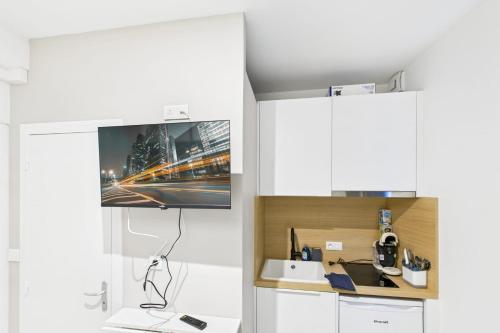 une cuisine avec des armoires blanches et une télévision au mur dans l'établissement Bleu saphir, à Troyes
