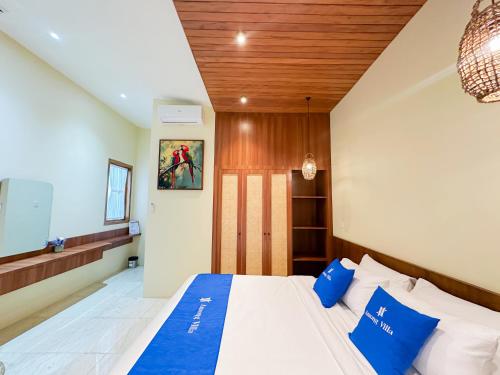 a bedroom with a large bed with blue pillows at Among Villa in Yogyakarta