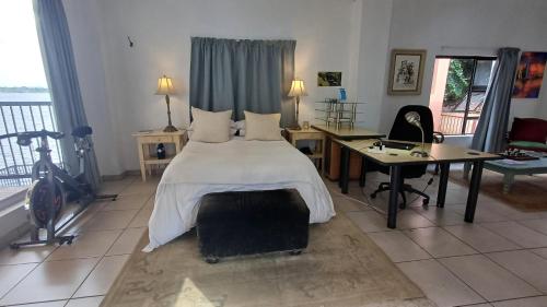 a bedroom with a bed and a desk and a bike at Harties Boathouse in Hartbeespoort