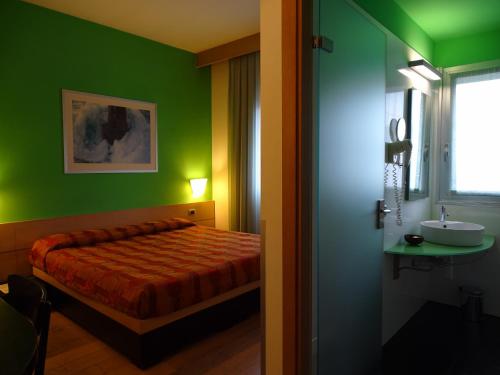 een slaapkamer met groene muren, een bed en een wastafel bij Hotel I Cedri in Scandicci
