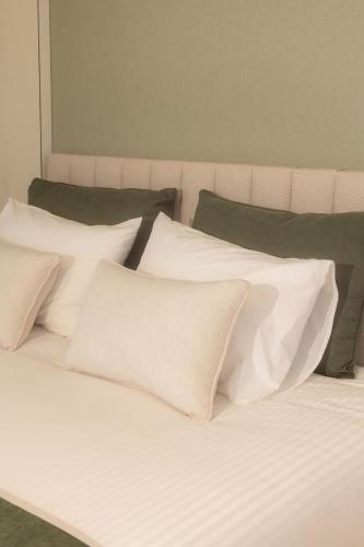 a bed with white pillows and green pillows at BLUE residence apartment in Póvoa de Varzim