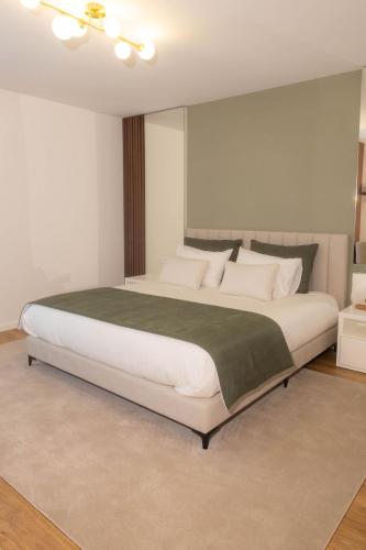 a bedroom with a large bed with a green blanket at BLUE residence apartment in Póvoa de Varzim