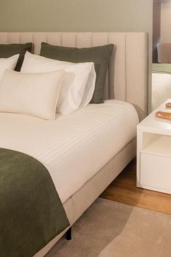 a bed with white sheets and green pillows on it at BLUE residence apartment in Póvoa de Varzim