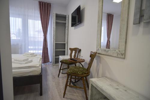 a room with a bed and two chairs and a mirror at Süni Vendégház in Căpîlniţa