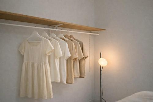 a room with a rack with white shirts and a lamp at Cozy Japandi Stay on Sukhumvit in Bangkok