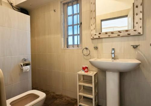 a bathroom with a sink and a toilet and a mirror at South Roots in Unawatuna
