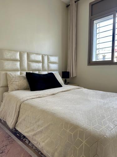 a bedroom with a large white bed with a window at Séjour Confort clim Navette Aéroport in Salé