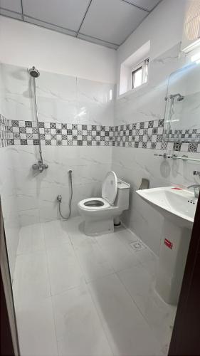 a white bathroom with a toilet and a sink at Hotel Araamish in Peshawar