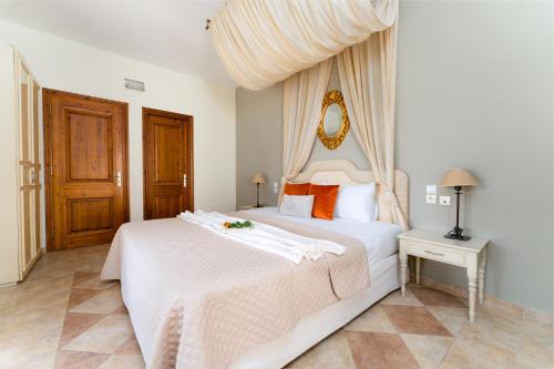 a bedroom with a large white bed with orange pillows at Ionian Coco Palm Beach Villas in Tsilivi