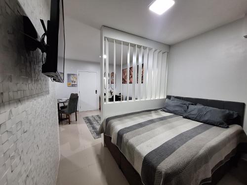 a bedroom with a bed and a table in it at Flat da Belly 904-A Hidro Piscina Praia in São Vicente