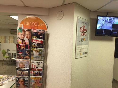 a display of magazines and posters on a wall at Premiere Classe St Etienne Nord Villars in Villars