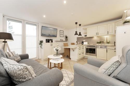 a living room with two couches and a kitchen at Haus Strandgeflüster Sandbank in Grömitz
