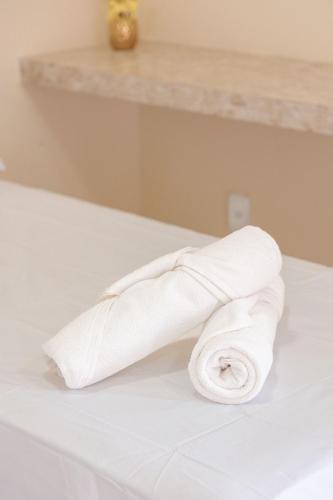 a roll of white toilet paper sitting on a bed at Pousada Carnaúbas - Sobral in Sobral
