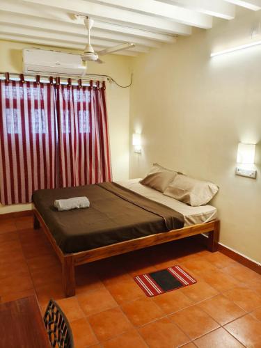 a bedroom with a bed and a red curtain at La Maison D'Ellappa in Pondicherry