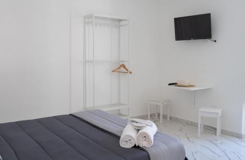 a white bedroom with a bed and a tv at Renna's in Grammichele