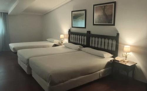 two beds in a hotel room with two lamps at Hotel Conde Rodrigo II by eme hoteles in Ciudad-Rodrigo