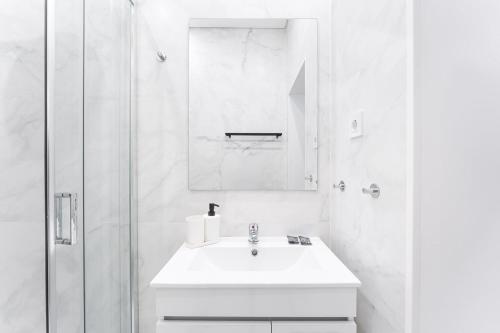 a white bathroom with a sink and a mirror at GuestReady - Douro D'or Apartments in Vila Nova de Gaia