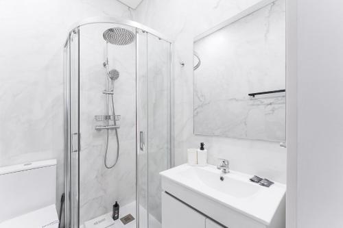 a white bathroom with a shower and a sink at GuestReady - Douro D'or Apartments in Vila Nova de Gaia