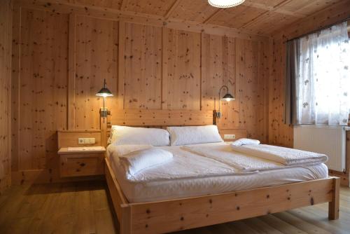 a bedroom with a large bed in a wooden wall at Das DolomitenNest in Dölsach